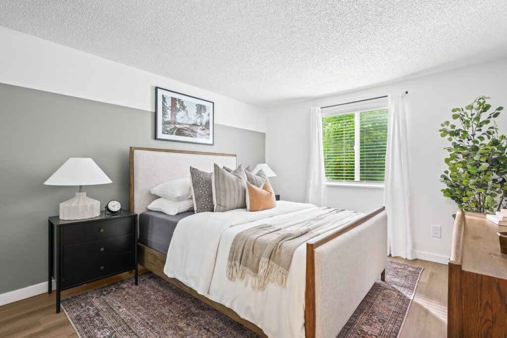 Bedroom with gray accent wall and large window at The Alden apartments in Tualatin