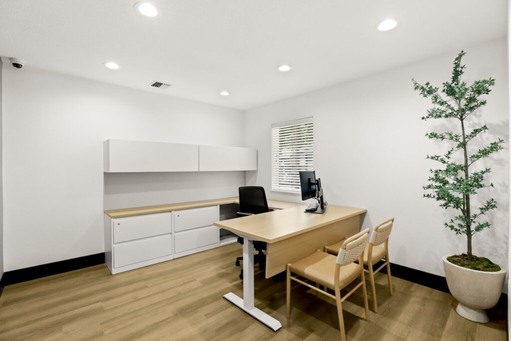 Office space with desk, computer, file cabinets, and chairs.
