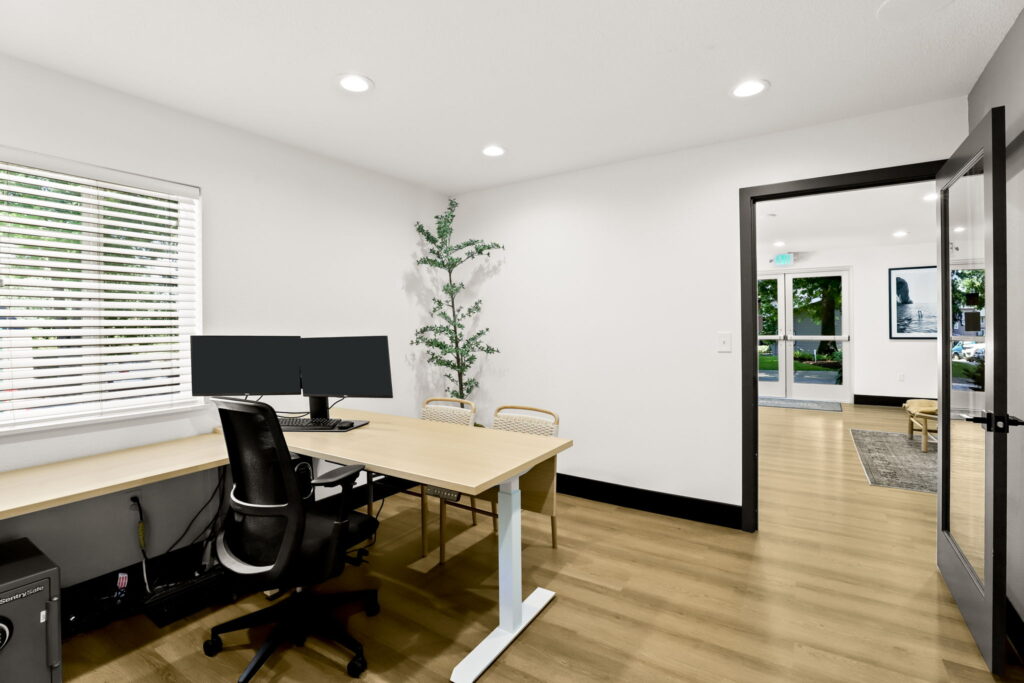 Office space with desk, computer, file cabinets, and chairs.